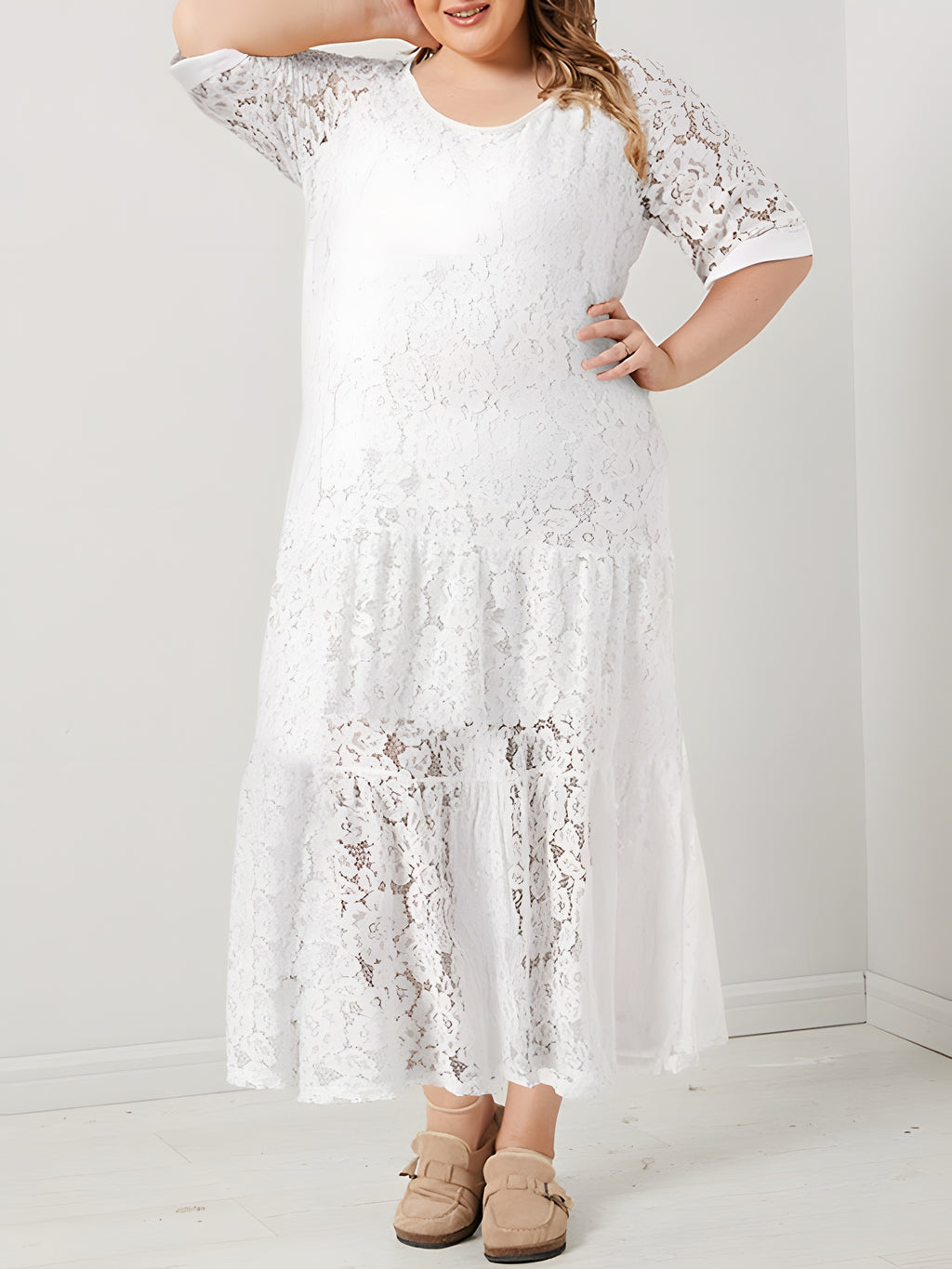 Modèle souriante grande taille portant la robe longue en dentelle bohème blanche