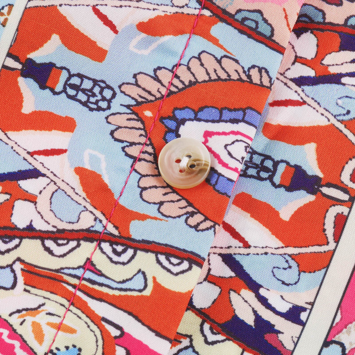 Macro du tissu de la blouse hippie, bouton nacré et surpiqûre rose sur imprimé cachemire Bild
