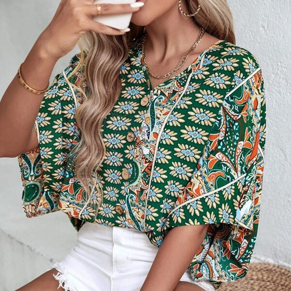 Blouse hippie vert forêt à imprimé fleuri et col en V boutonné, portée avec un short blanc Bild