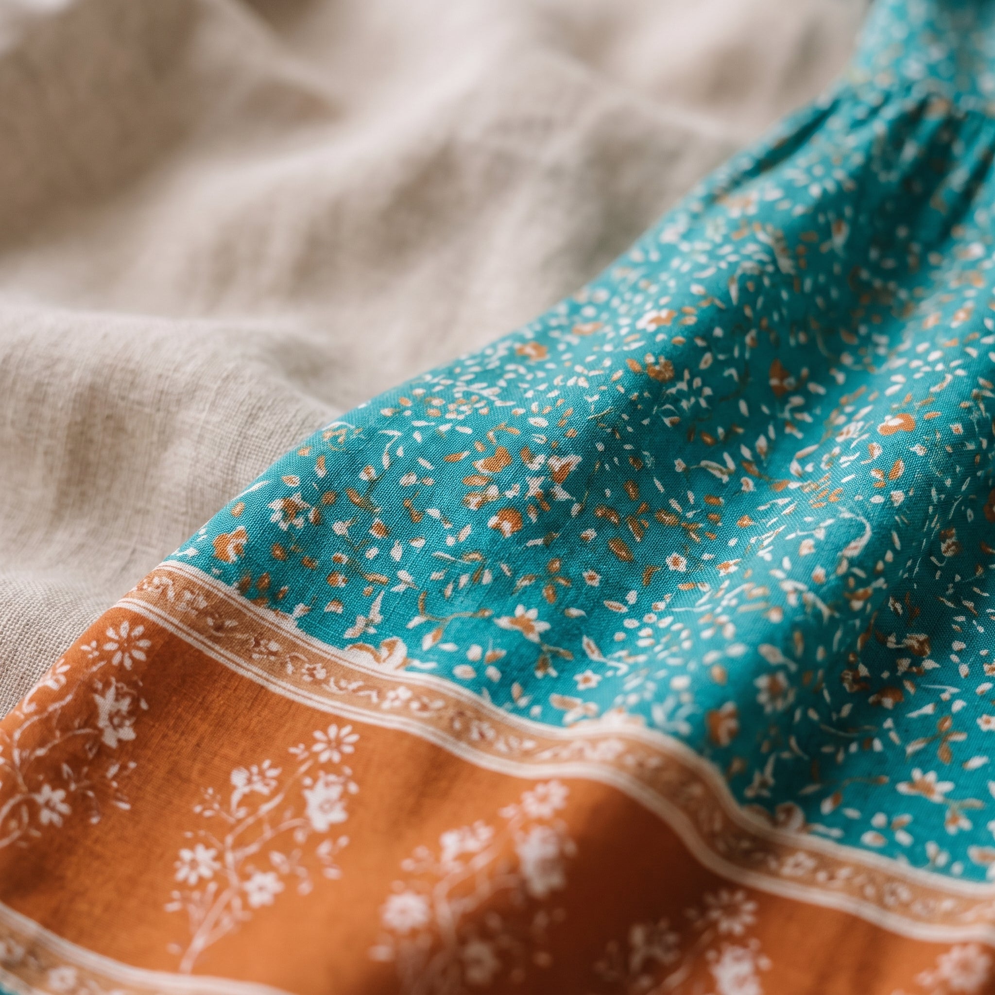 Détail de l'imprimé fleuri turquoise et de la bordure terracotta de la robe hippie Bild