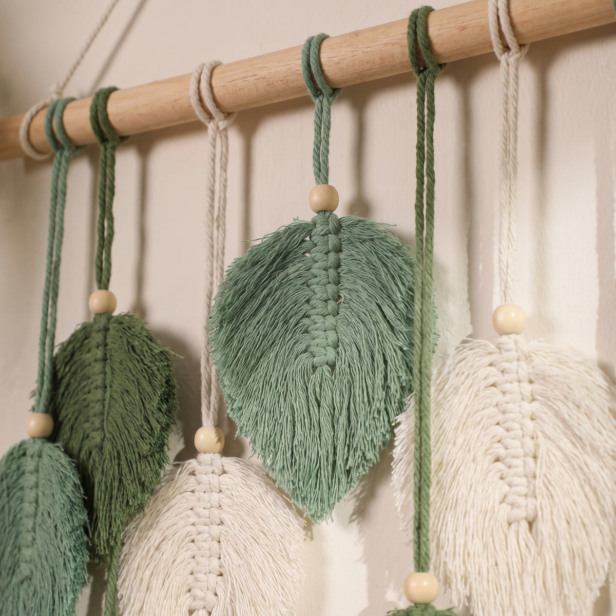 Détail des feuilles de coton frangées, perle de bois et branche de la tapisserie macramé Bild