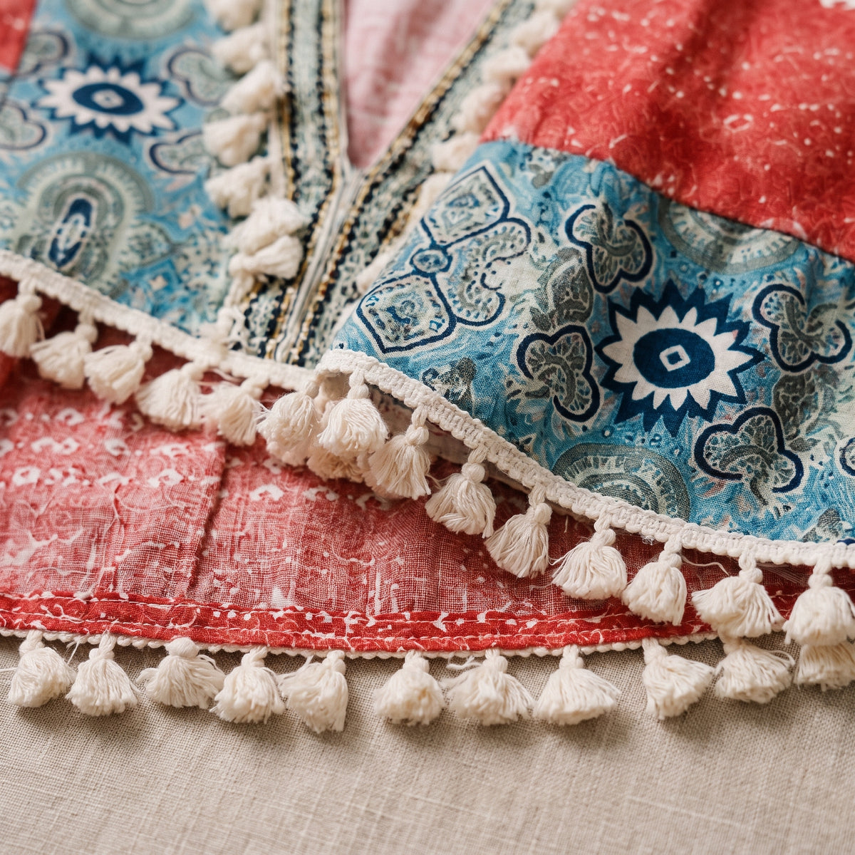 Macro des pompons crème et de l'imprimé patchwork terracotta et bleu de la robe hippie chic Bild