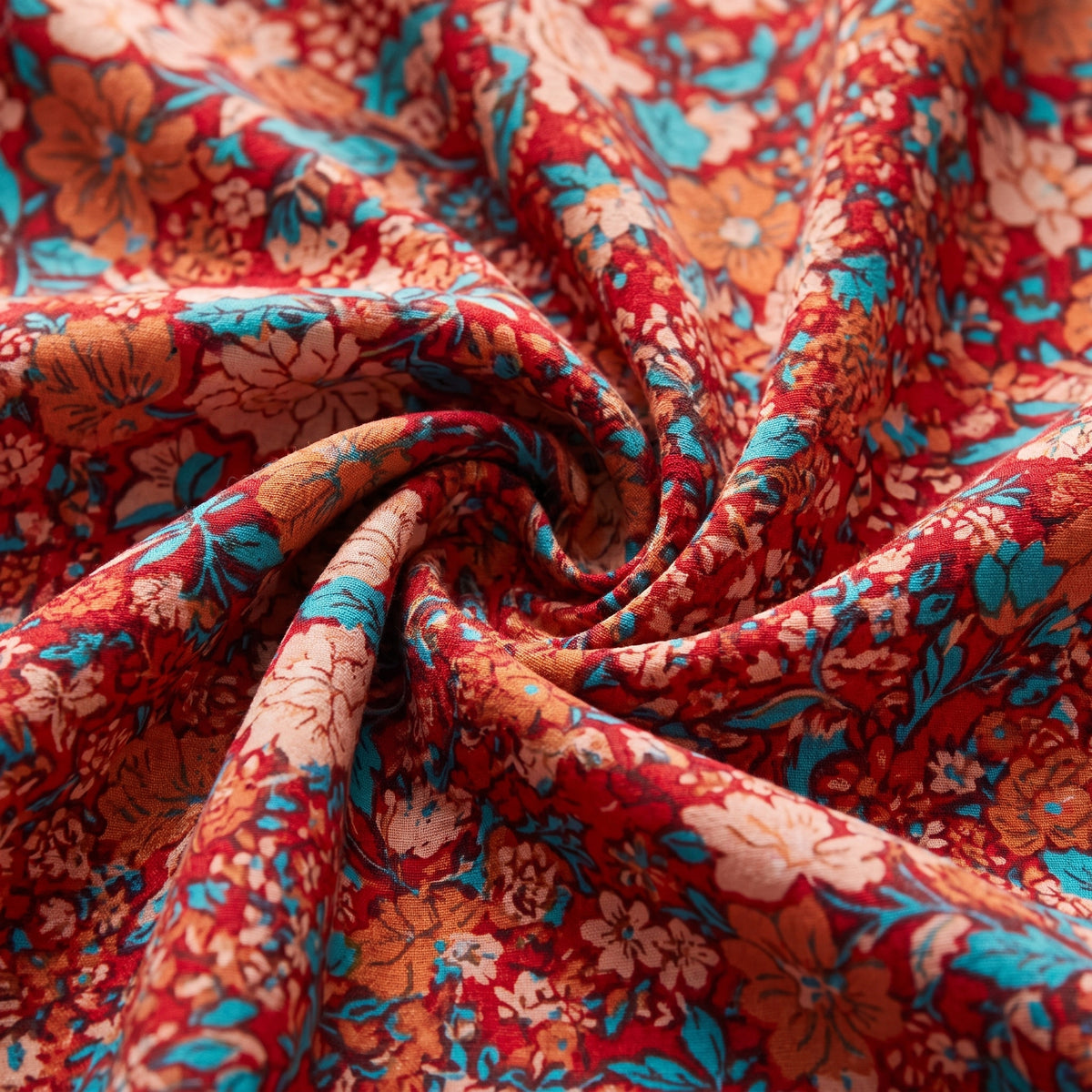 Gros plan de l’imprimé floral corail, orange et turquoise de la combinaison hippie femme fleurie