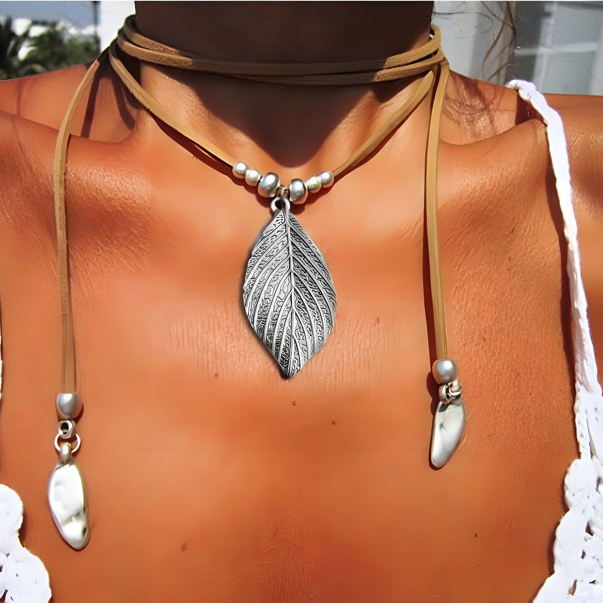 Collier bohème hippie porté, pendentif feuille gravée argentée sur cordon daim
