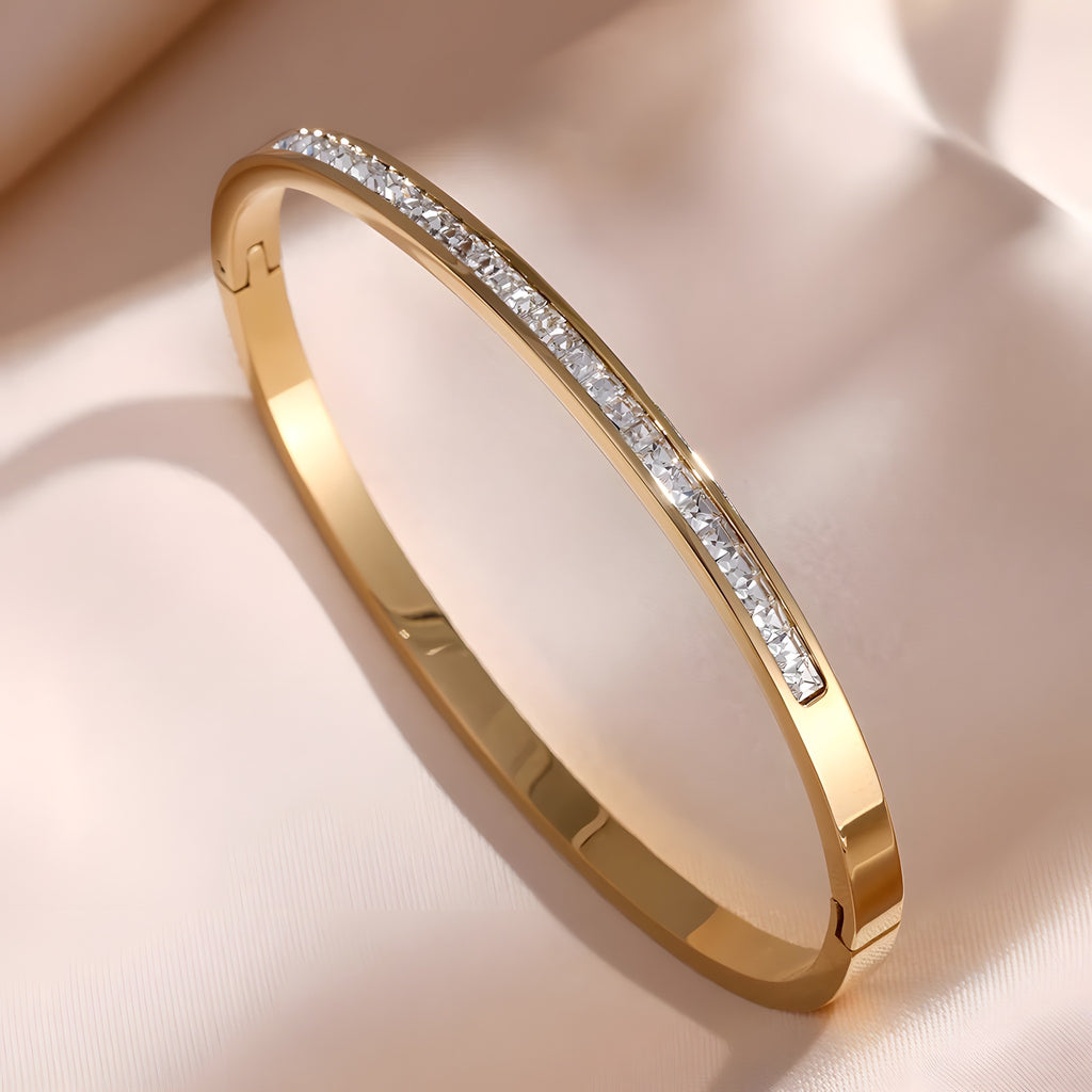 Bracelet jonc or à rang de zircons taille princesse, fermoir clip, sur satin champagne