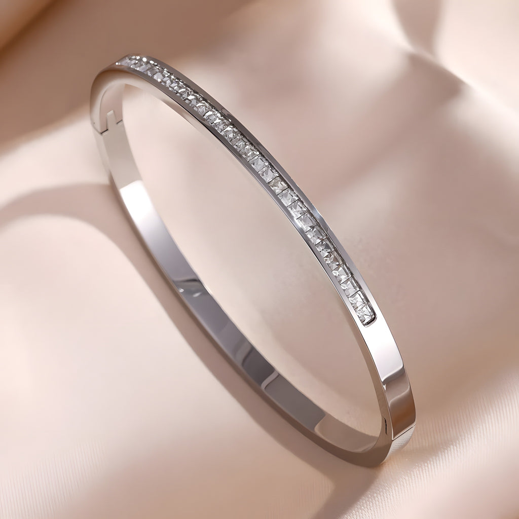 Bracelet jonc argent à rang de zircons taille princesse, fermoir clip, sur satin champagne