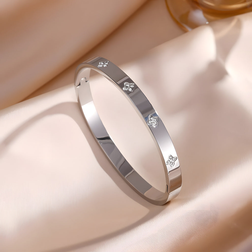 Bracelet jonc argent à motifs quadrilobes sertis de zircons, fermoir clip, sur satin champagne