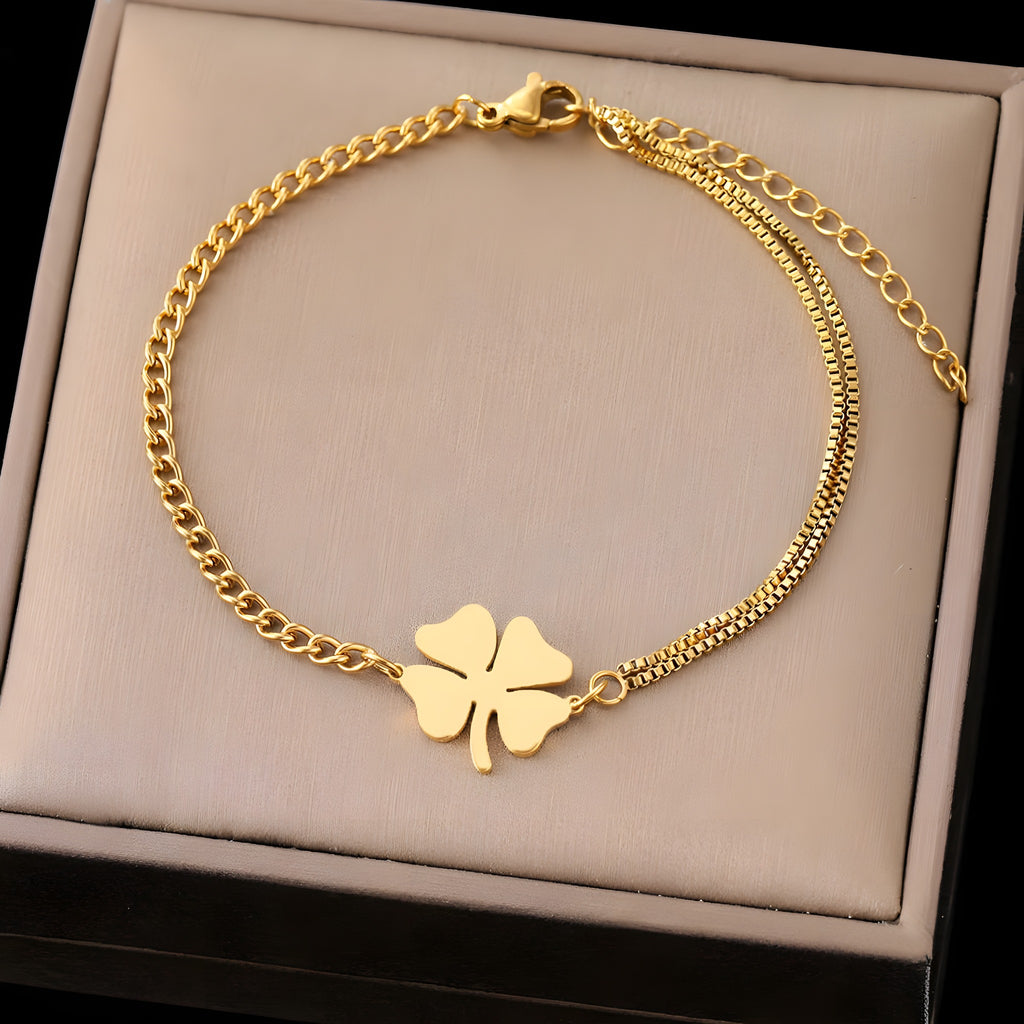 Bracelet trèfle 4 feuilles doré à plat dans un écrin beige, chaîne asymétrique