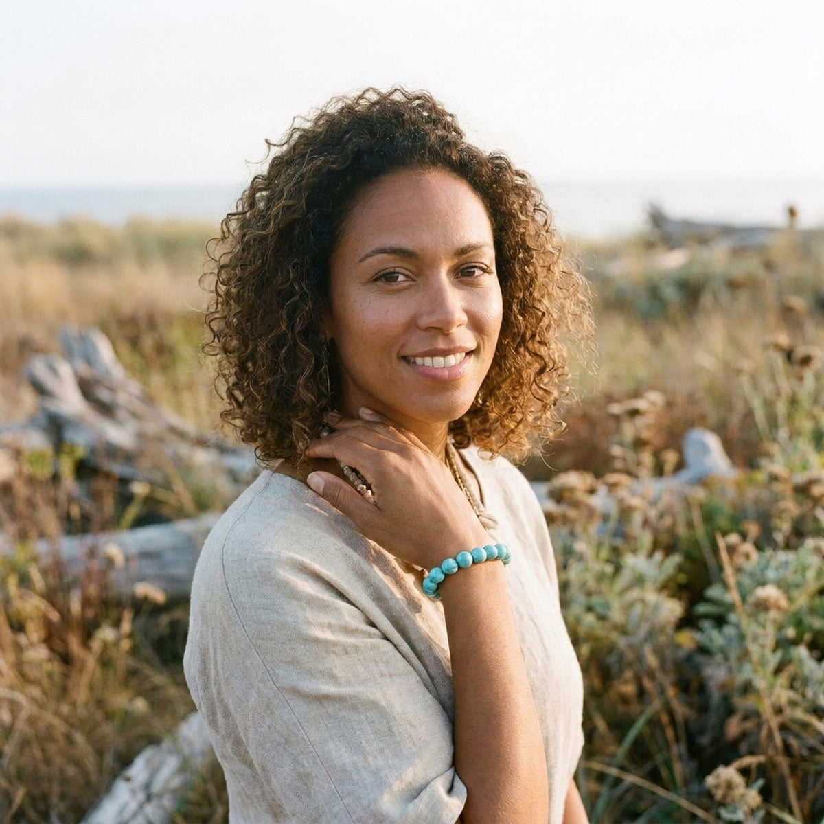 Femme souriante portant le bracelet turquoise au poignet, décor nature bohème