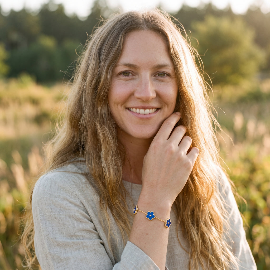 Modèle souriante portant le bracelet fleur 5 pétales bleu au poignet, ambiance bohème en lumière dorée