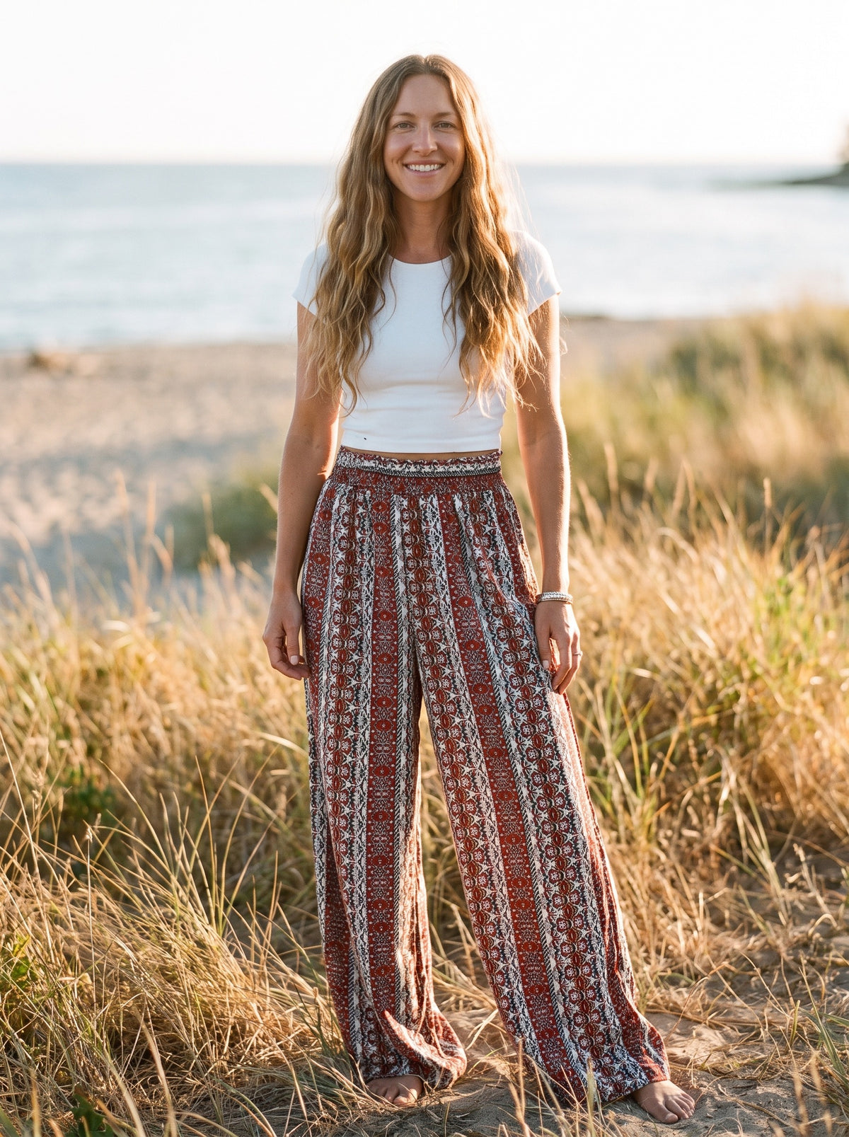 Femme souriante portant le pantalon hippie large imprimé ethnique au bord de mer