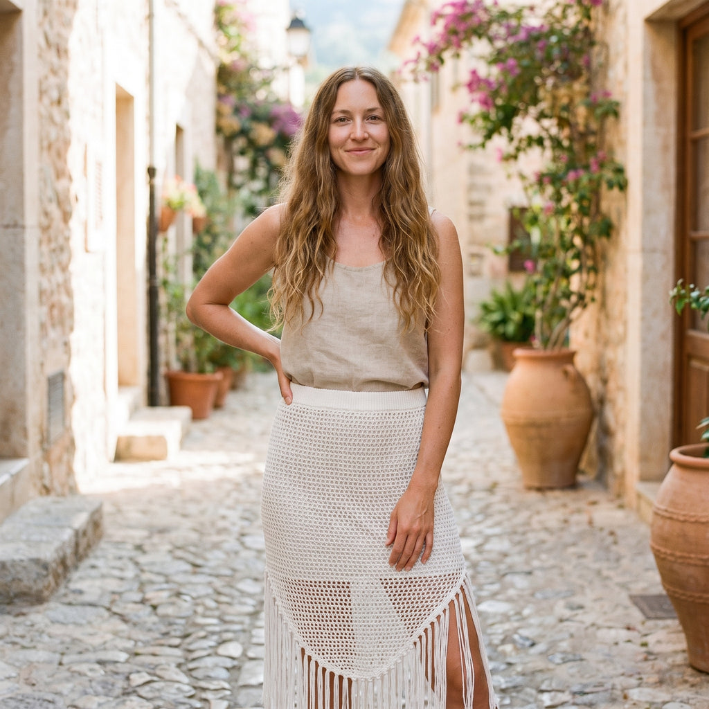 Modèle souriante portant le cache maillot jupe en crochet blanc dans une ruelle méditerranéenne