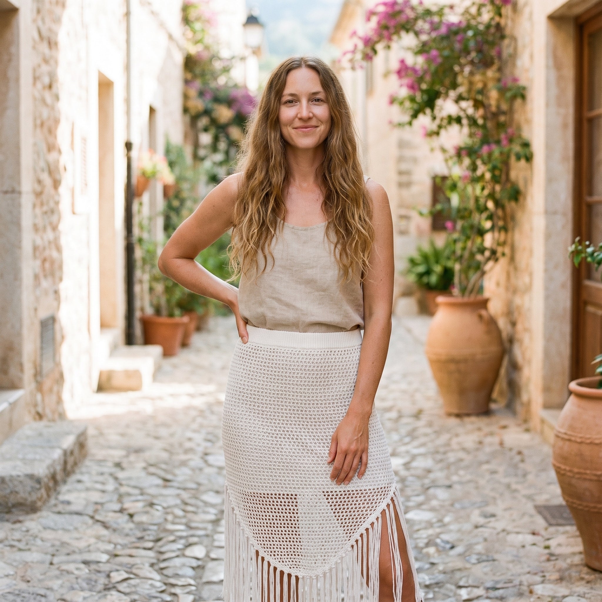 Modèle souriante portant le cache maillot jupe en crochet blanc dans une ruelle méditerranéenne Image