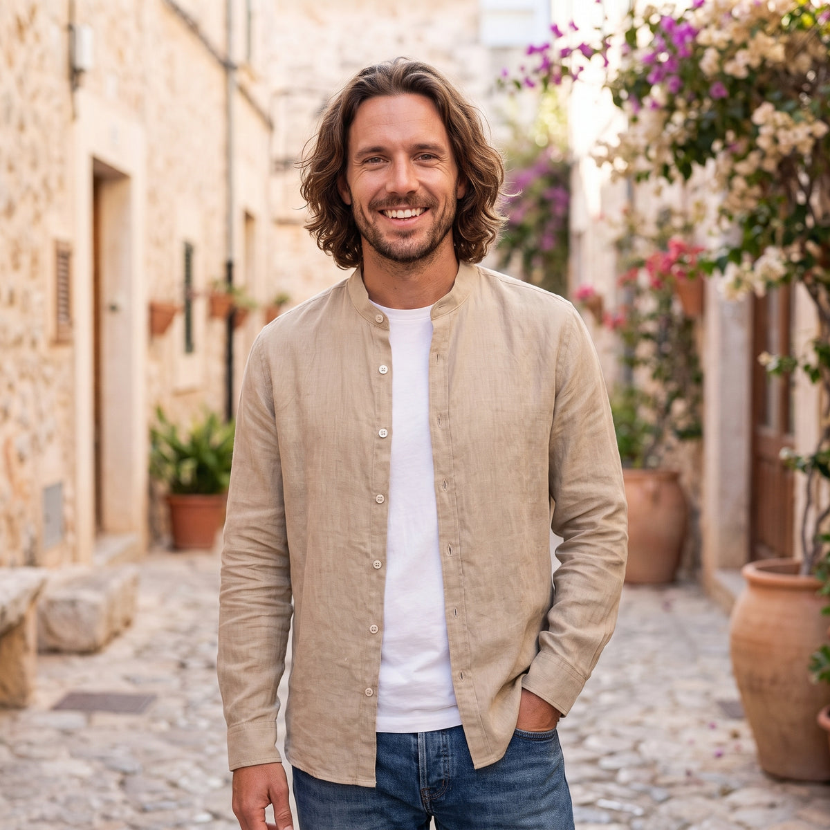 Modèle souriant portant la chemise hippie homme effet lin beige, en ruelle méditerranéenne