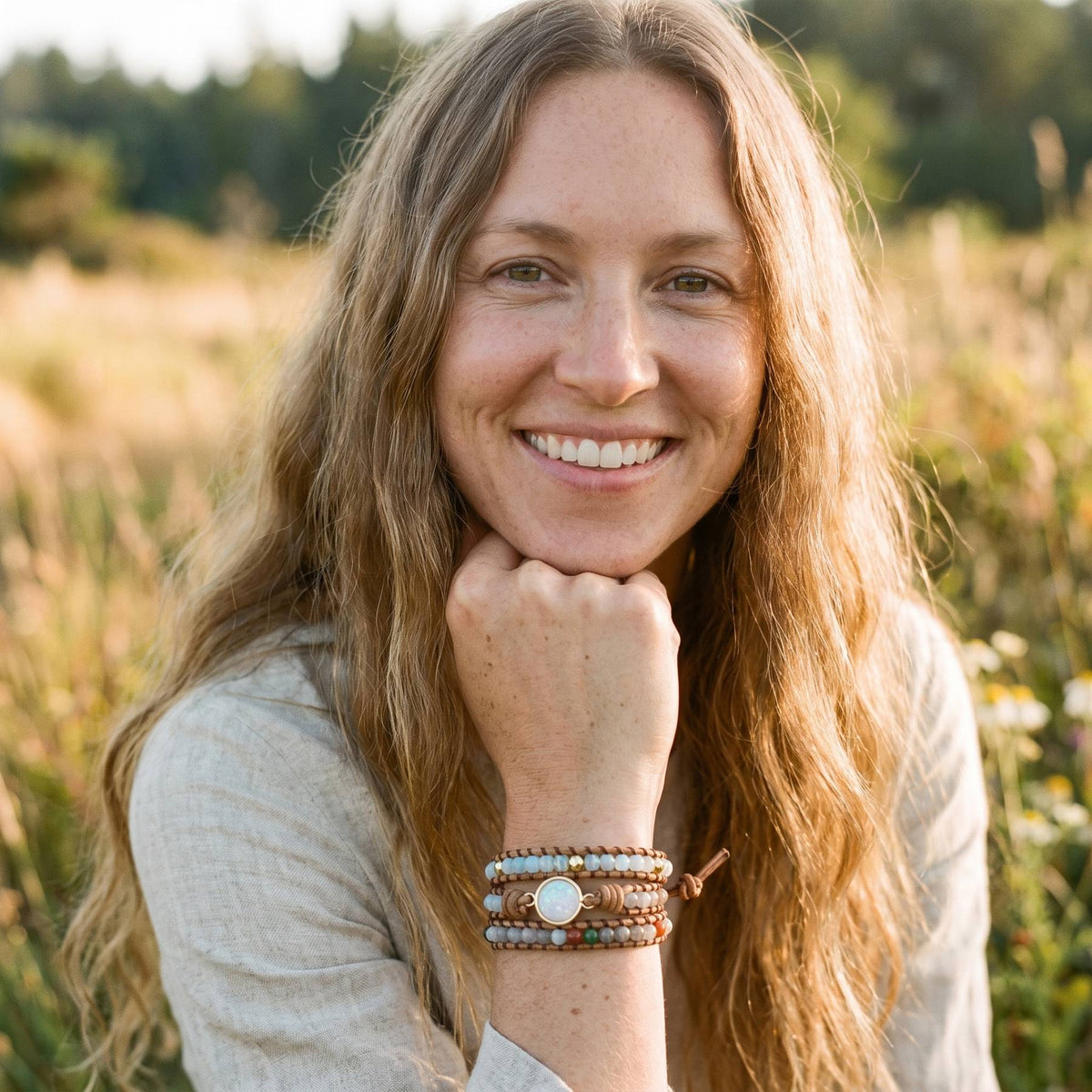 Femme souriante portant le bracelet wrap opale et agate au poignet, champ boheme golden hour