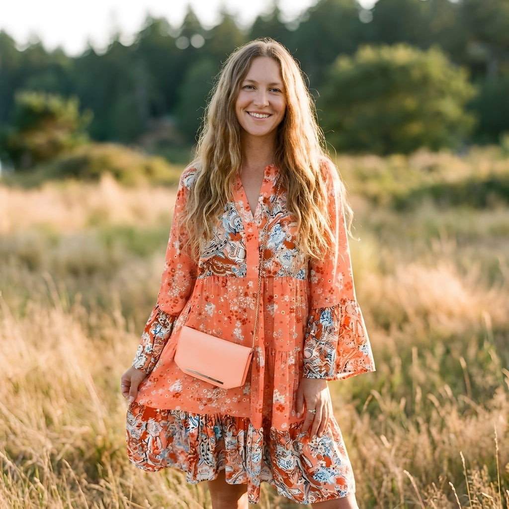 Robe bohème corail à imprimé fleuri portée par un modèle souriant en extérieur