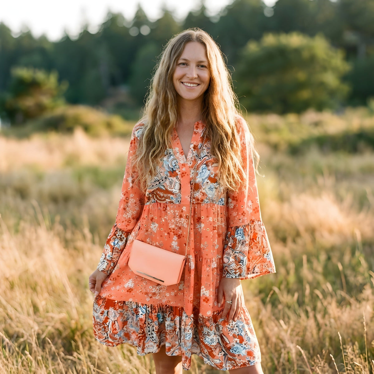 Robe bohème corail à imprimé fleuri portée par un modèle souriant en extérieur