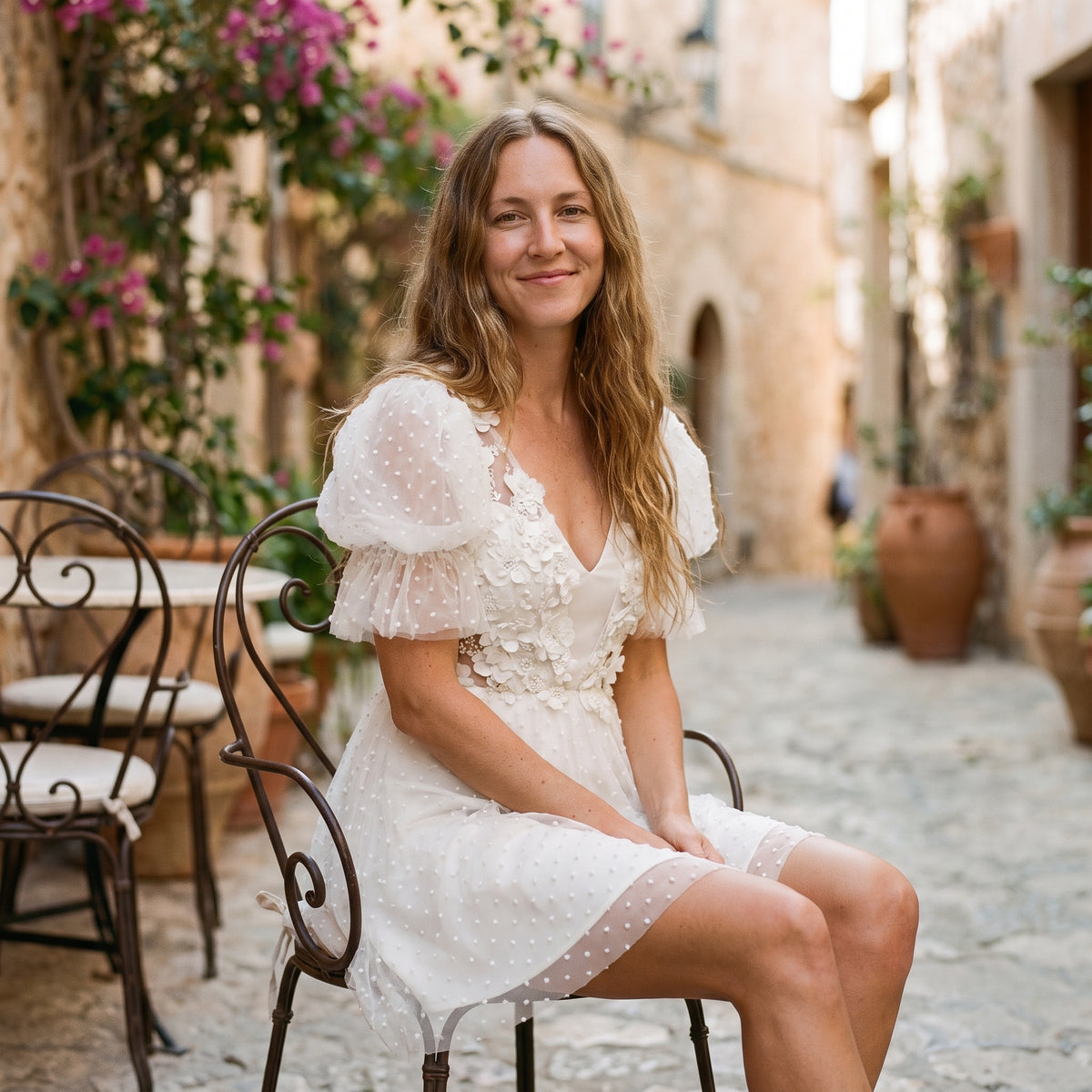 Modèle souriant assise en robe de mariée bohème courte, terrasse méditerranéenne