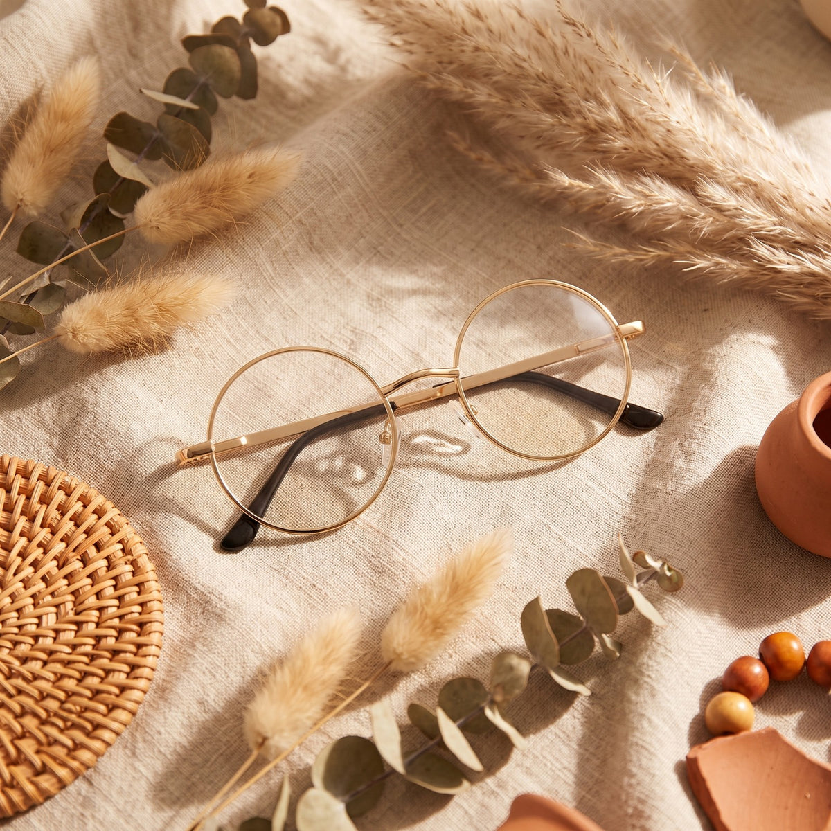 Lunettes rondes John Lennon dorées posées dans un décor bohème nature Image