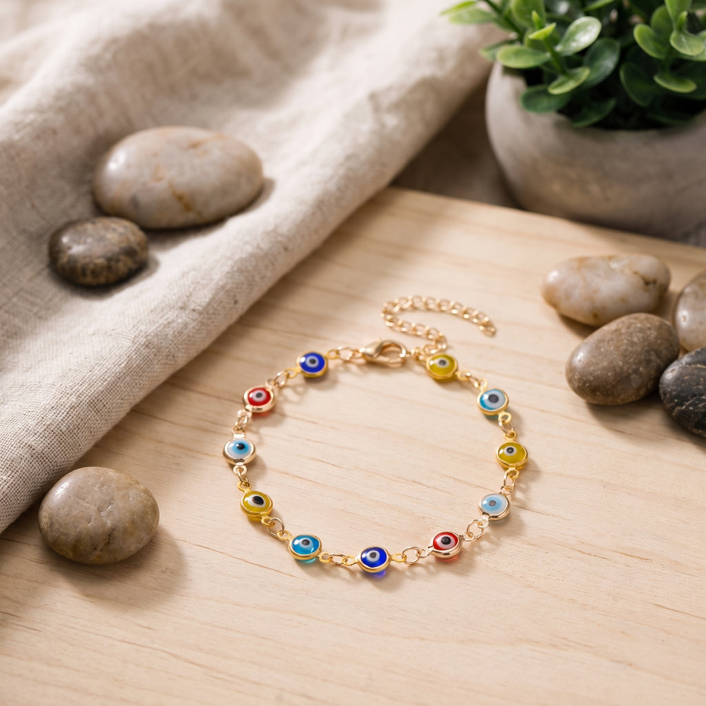 Bracelet mauvais œil multicolore posé sur un bois clair avec lin et galets, décor bohème