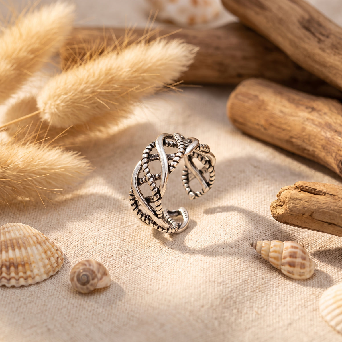 Bague tressée hippie argentée posée sur lin bohème
