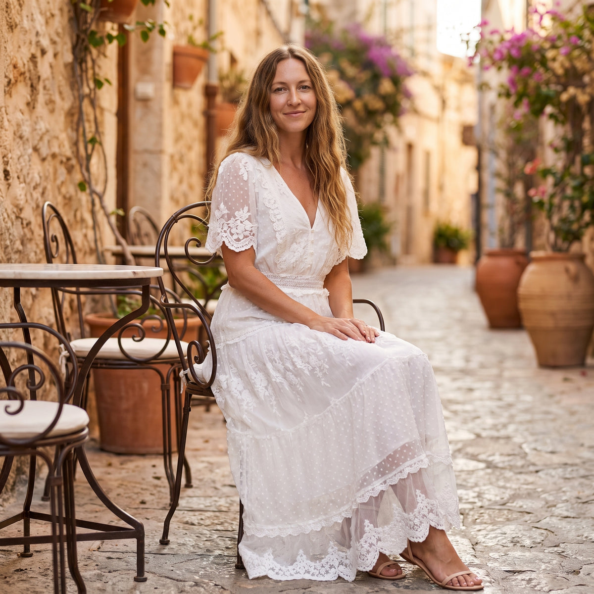 Modèle souriant en robe longue blanche bohème, terrasse méditerranéenne