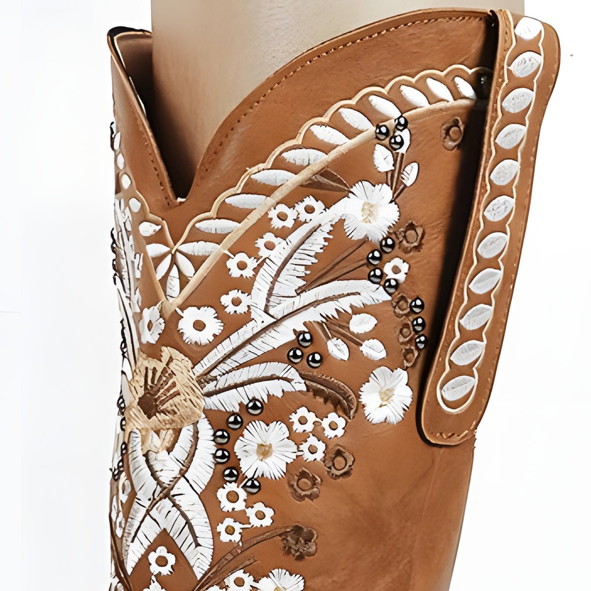 Gros plan de la broderie florale blanche et des clous sur le cuir camel