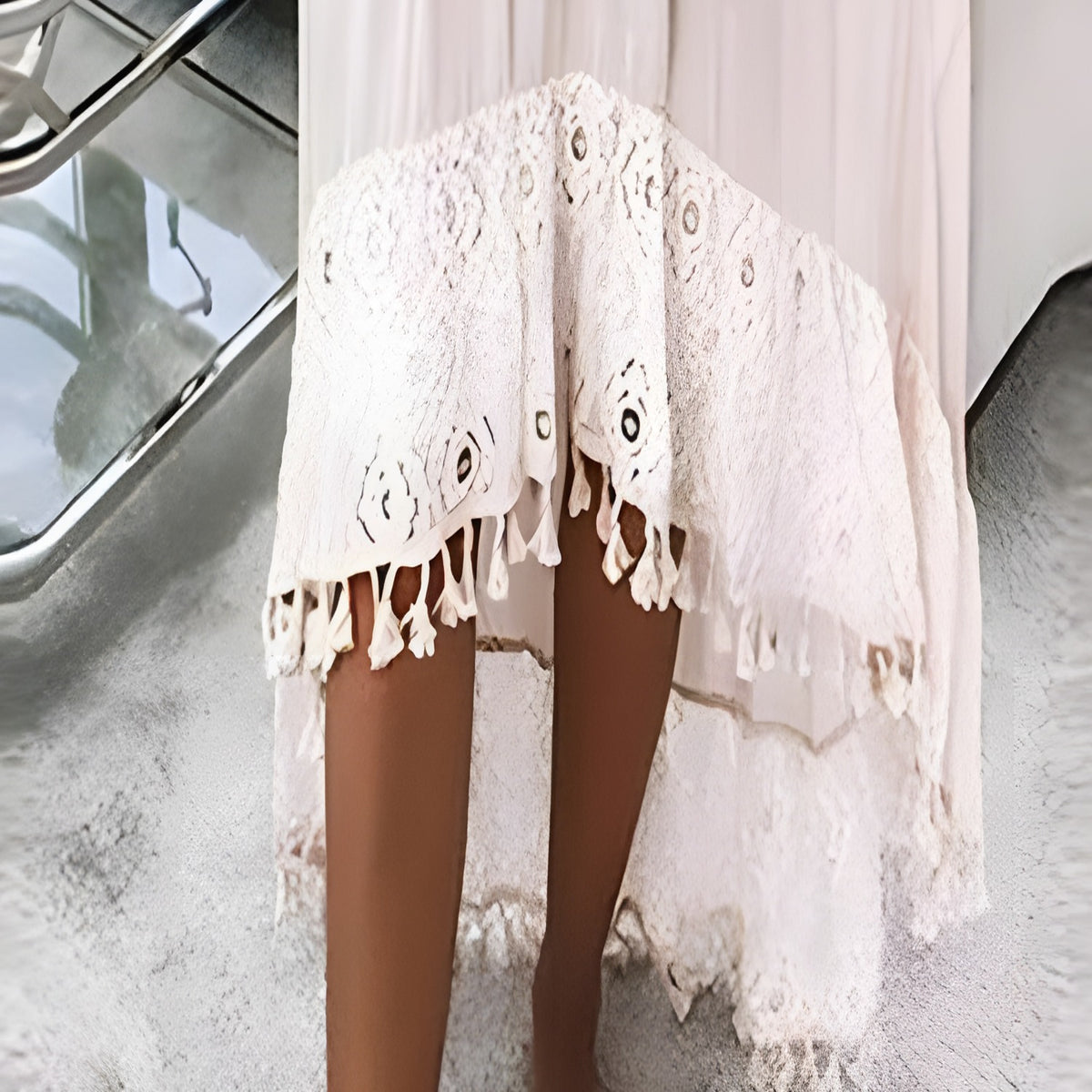 Gros plan de l'ourlet asymétrique en dentelle à mini-pompons