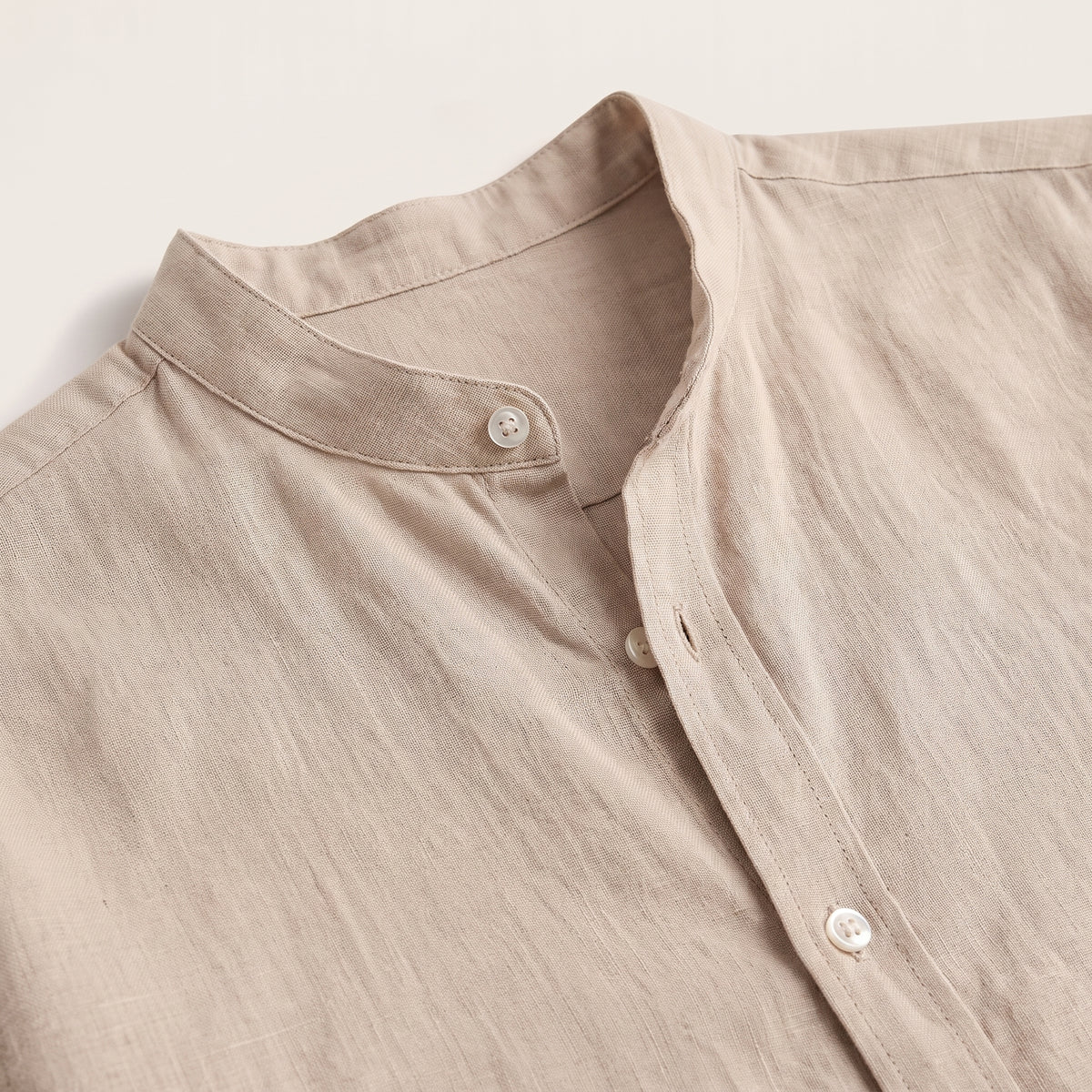 Gros plan col mao et tissu effet lin beige de la chemise hippie, fond studio