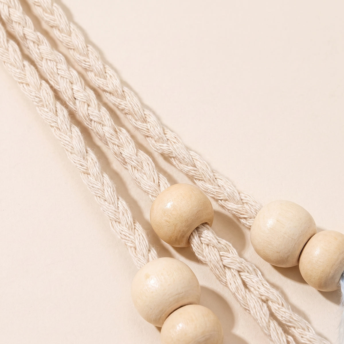 Gros plan du cordon tressé écru et des perles de bois du bandeau à plumes hippie Image