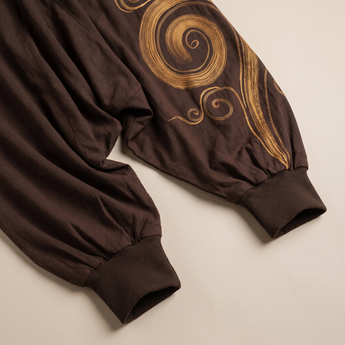 Bas du sarouel homme marron, bord côte resserré et spirale dorée sur le côté