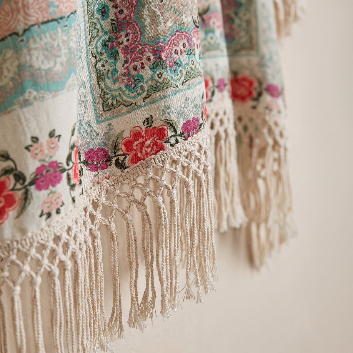 Gros plan sur la frange macramé et l’imprimé floral du gilet kimono