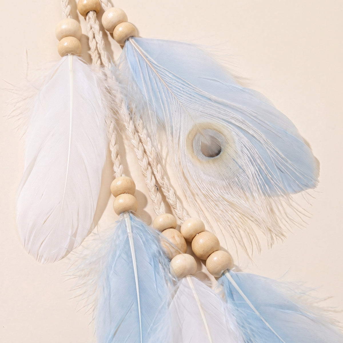 Gros plan des plumes blanches et bleu pâle et des perles de bois du bandeau à plumes hippie