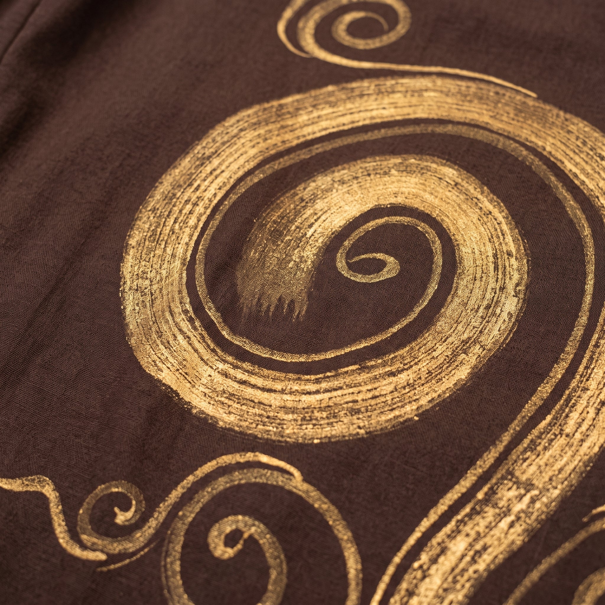 Détail de la grande spirale dorée peinte à la main sur le sarouel homme marron Image