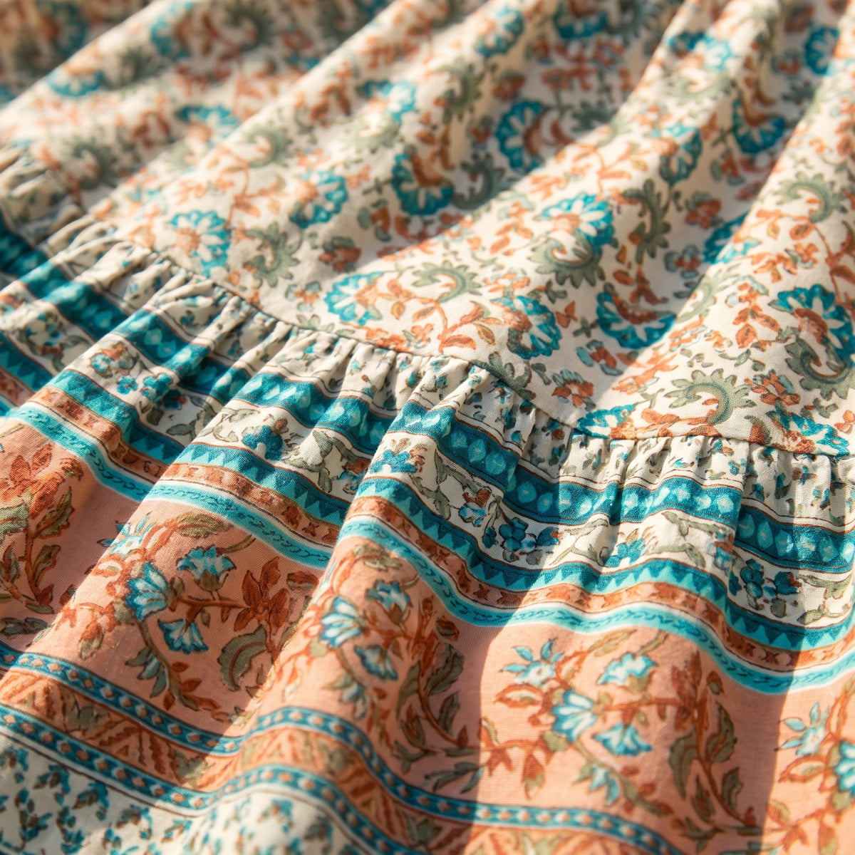 Détail de l’imprimé floral turquoise et corail et des bandes ethniques de la jupe hippie femme en coton Image