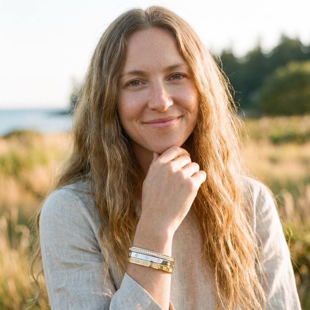Femme souriante portant trois bracelets joncs acier à zircons empilés (rang de zircons, quadrilobes, chiffres romains)