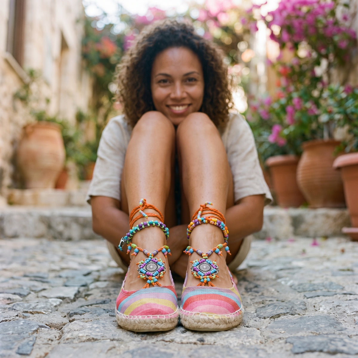 Espadrilles bohème rayées à lacets perlés portées par un modèle souriant, ruelle méditerranéenne