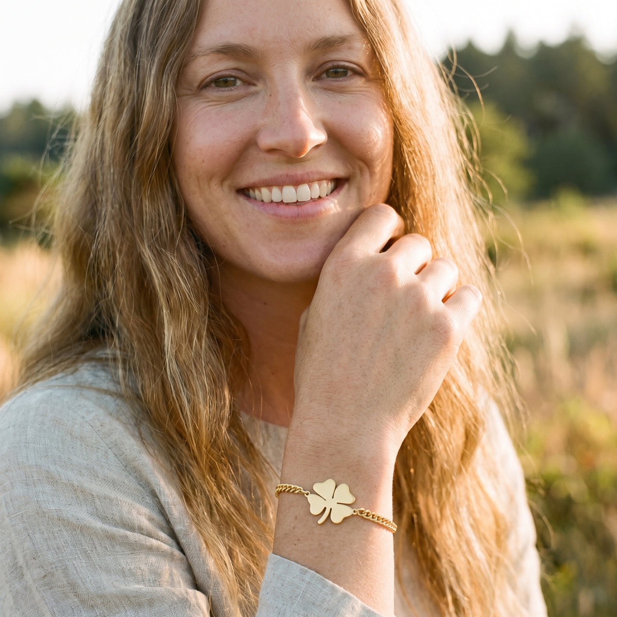 Femme souriante portant le bracelet trèfle 4 feuilles doré en acier inoxydable