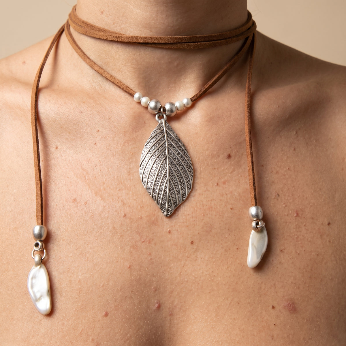 Collier bohème hippie porté, pendentif feuille gravée argentée sur cordon suédé