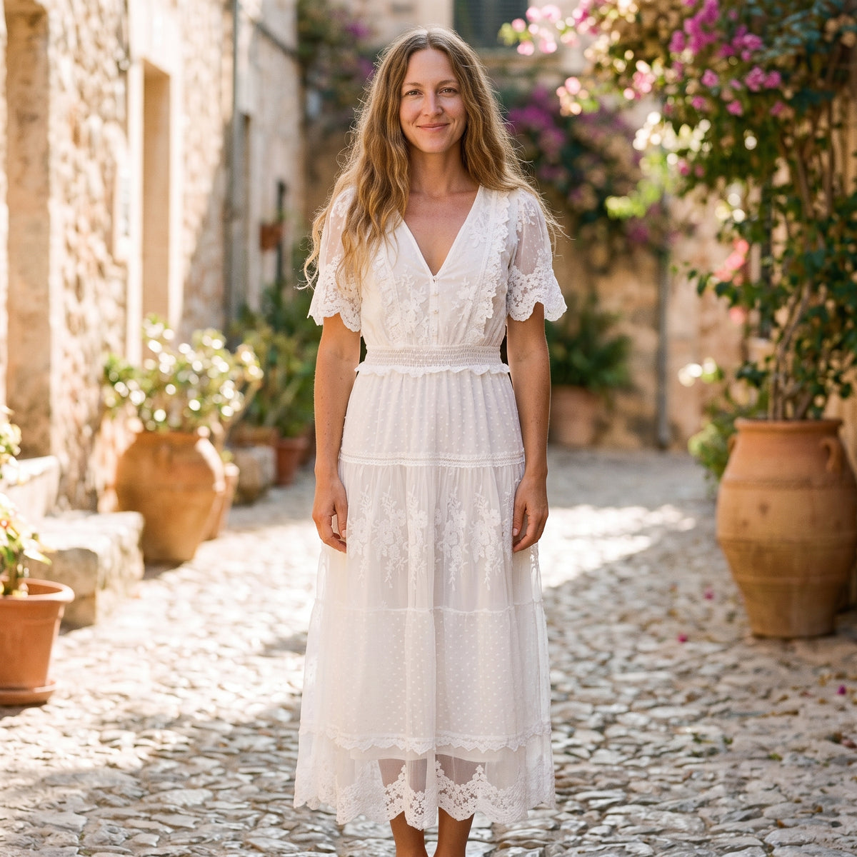 Robe longue blanche bohème à volants portée par un modèle souriant, ruelle méditerranéenne