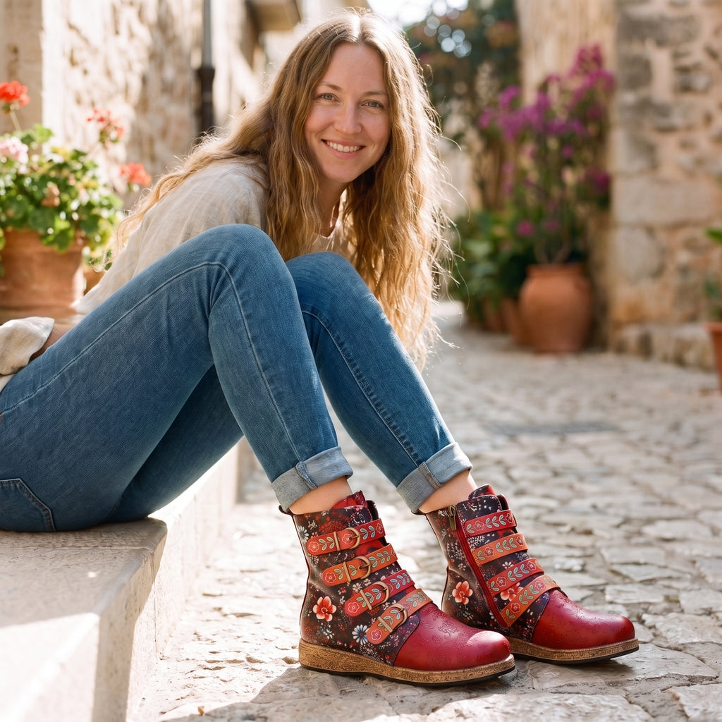 Modèle souriante portant les bottines bohème rouge à fleurs, assise dans une ruelle méditerranéenne