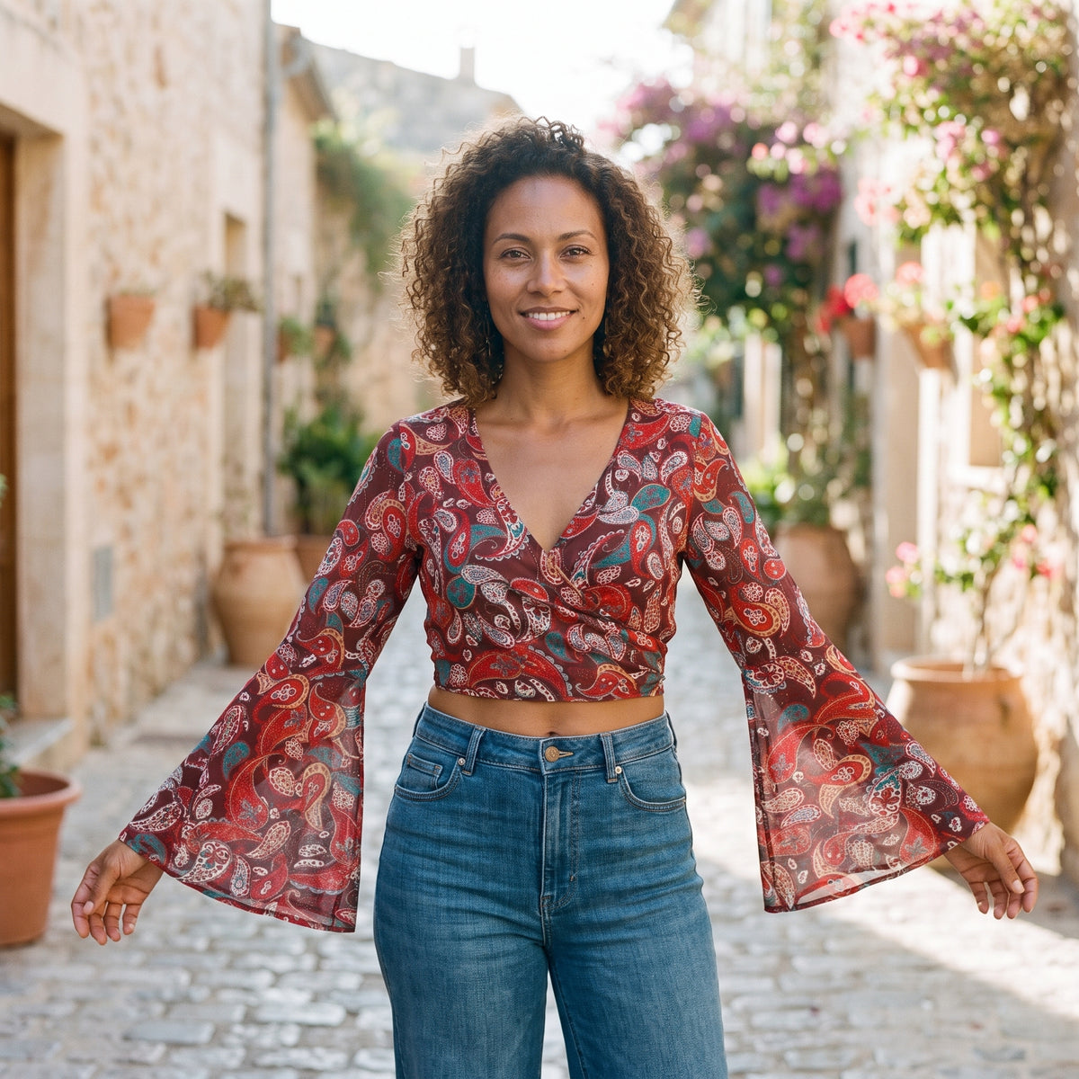 Crop-top bohème 70s cache-coeur rouge paisley à manches pagode porté par un modèle souriant