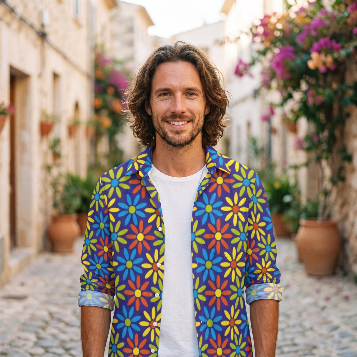 Modèle homme souriant portant la chemise à fleurs hippie bleue à marguerites rétro, ruelle méditerranéenne