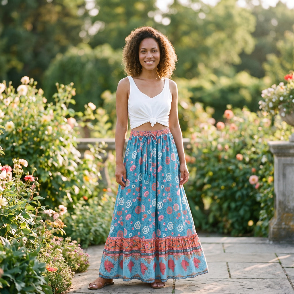 Jupe longue bohème turquoise à fleurs portée par un modèle souriant dans un jardin