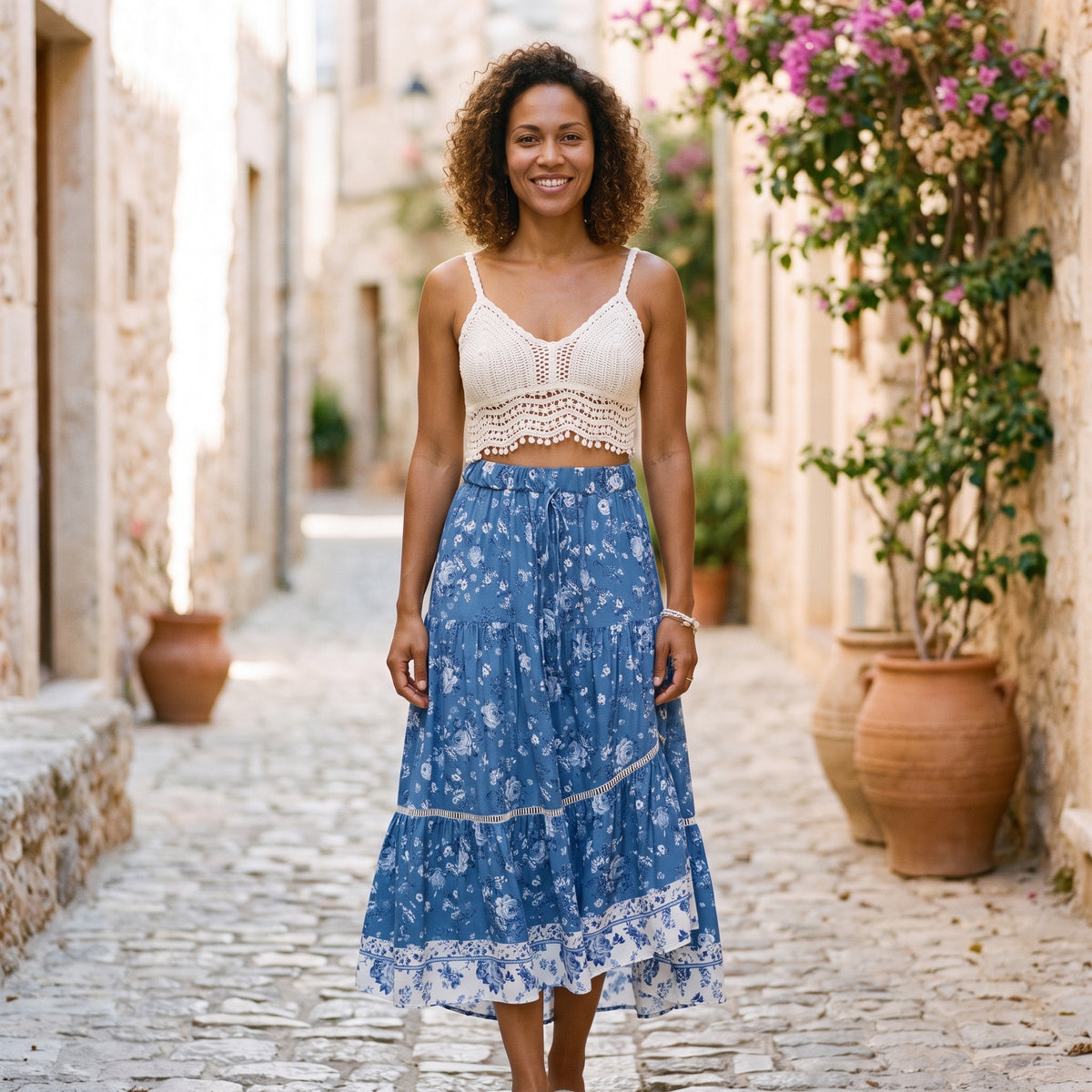 Jupe longue bohème bleu jean à fleurs portée par un modèle souriant en ruelle méditerranéenne