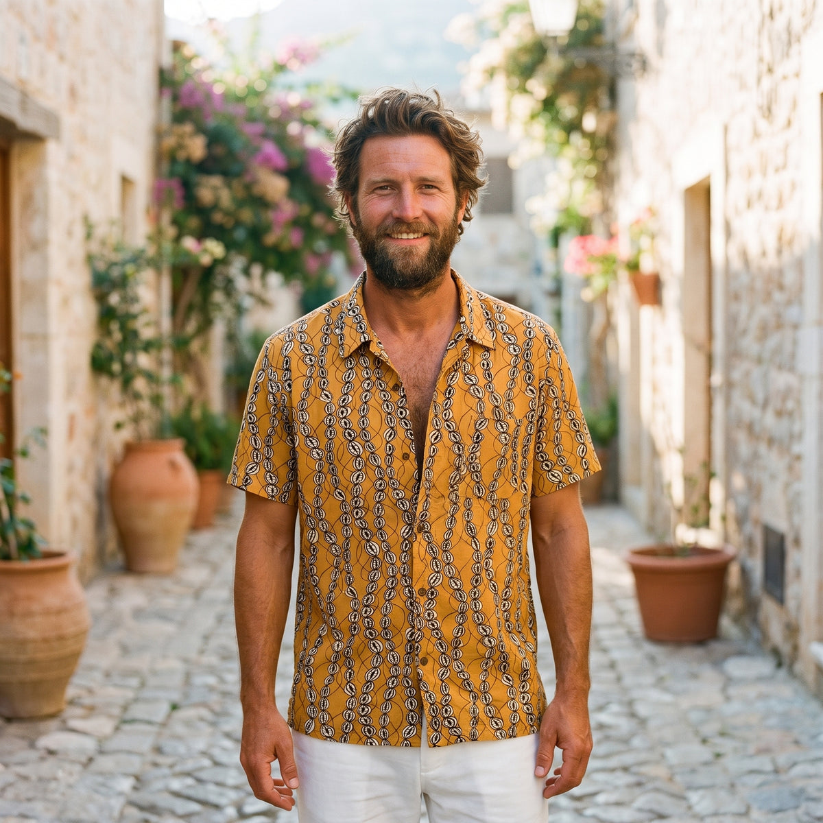 Chemise homme vintage imprimé ethnique moutarde portée par un modèle souriant en ruelle méditerranéenne