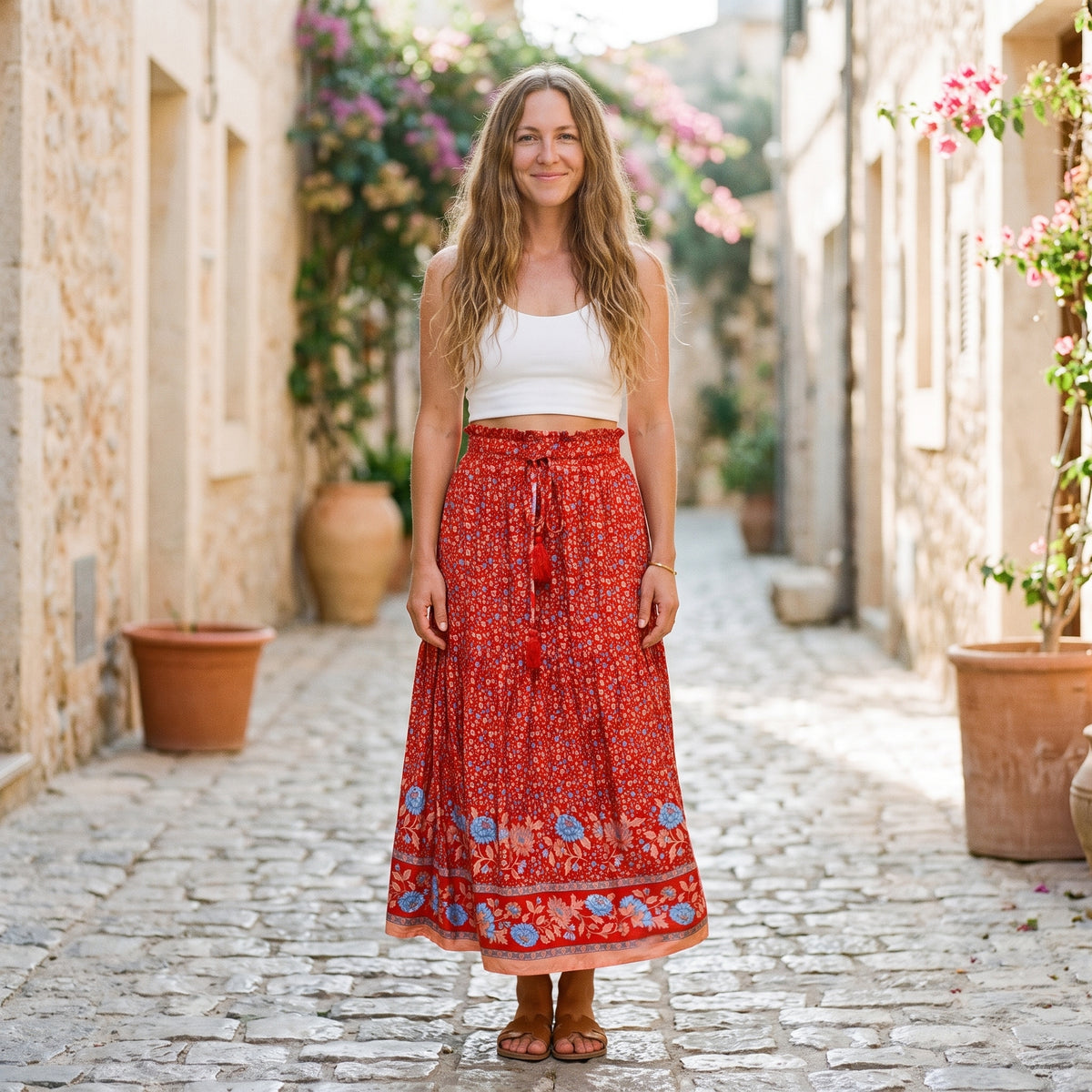 Jupe midi bohème rouge à fleurs portée par un modèle souriant, taille haute paperbag