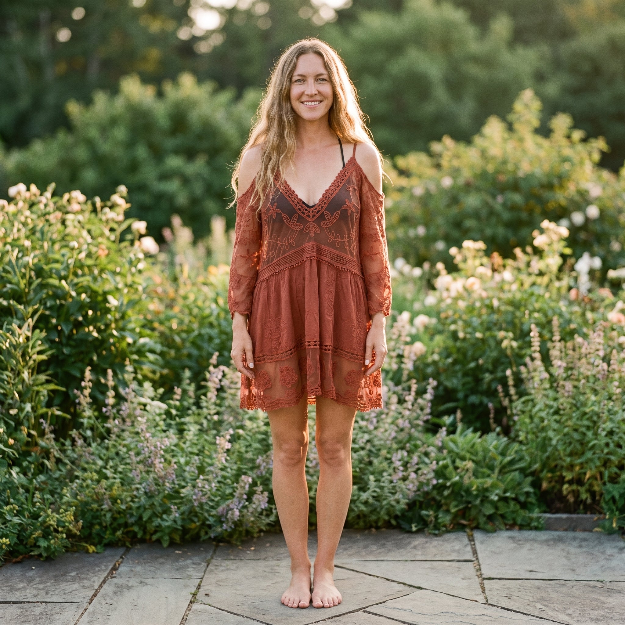 Tunique de plage en dentelle terracotta portée par un modèle souriant dans un jardin Bild