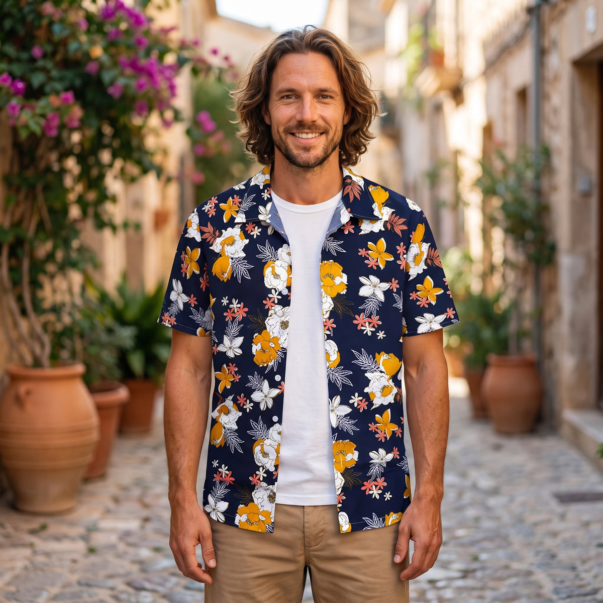 Chemise hawaïenne homme fleurs sur bleu marine portée par un modèle souriant en ruelle méditerranéenne