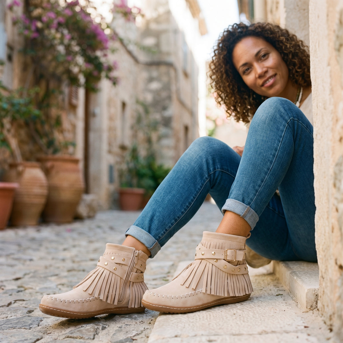 Modèle souriante portant les bottines mocassin à franges cloutées blanc cassé
